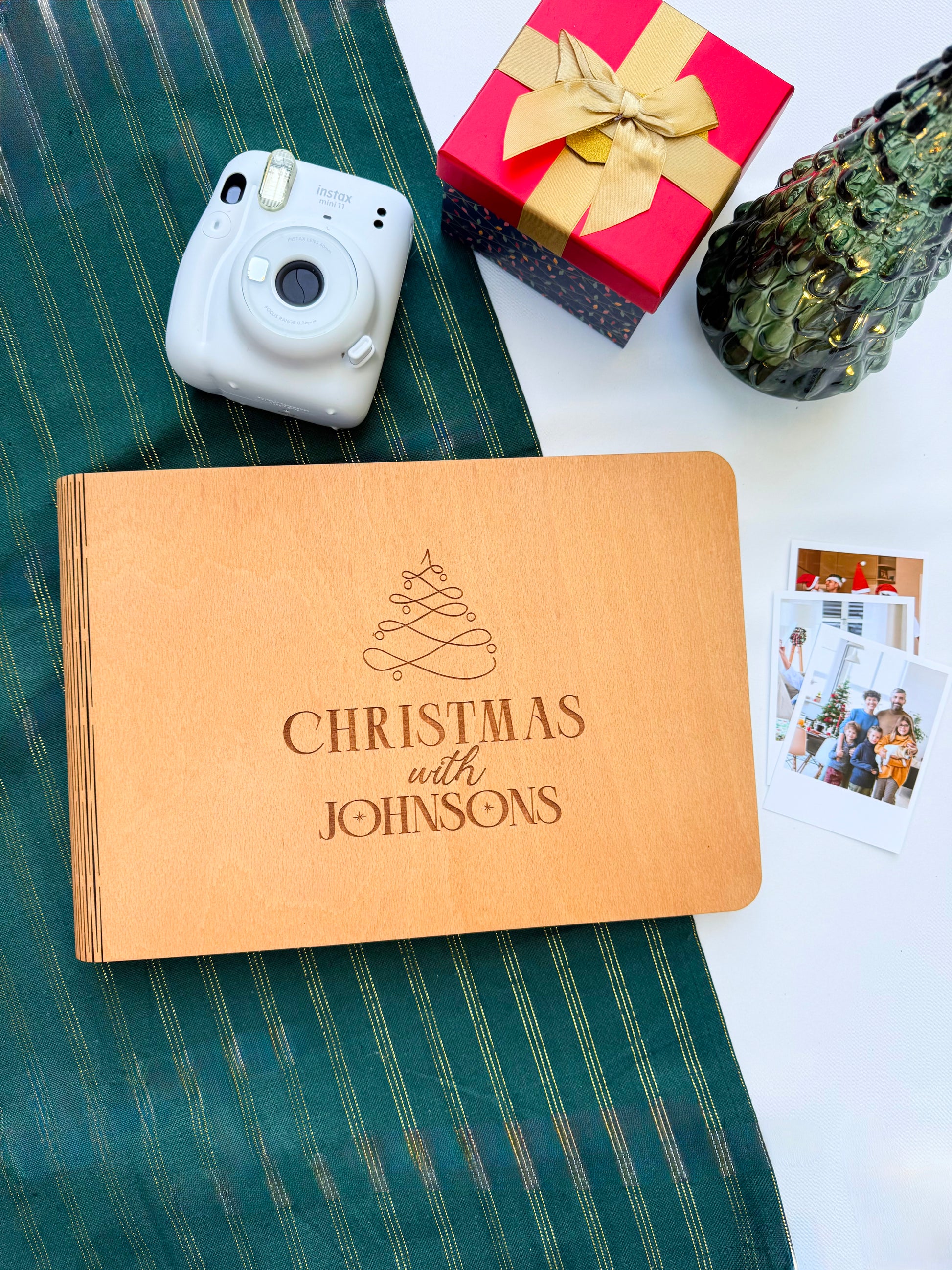 Personalized Christmas photo album with camera, gift, and photos on a green surface